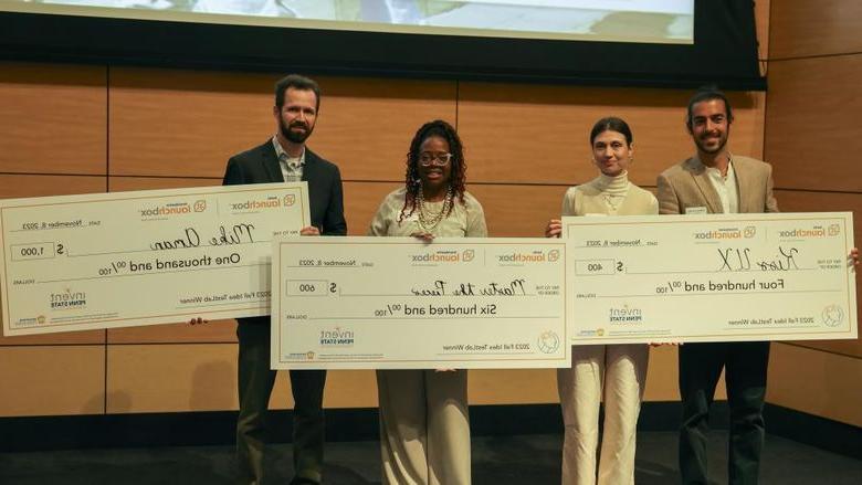 winners of idea TestLab competition standing on stage with large checks for $400, $600 and $1000